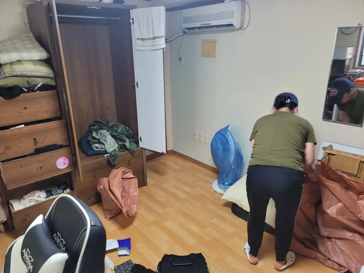 서랍장이 있는 방에서 짐을 정리하는 작업자