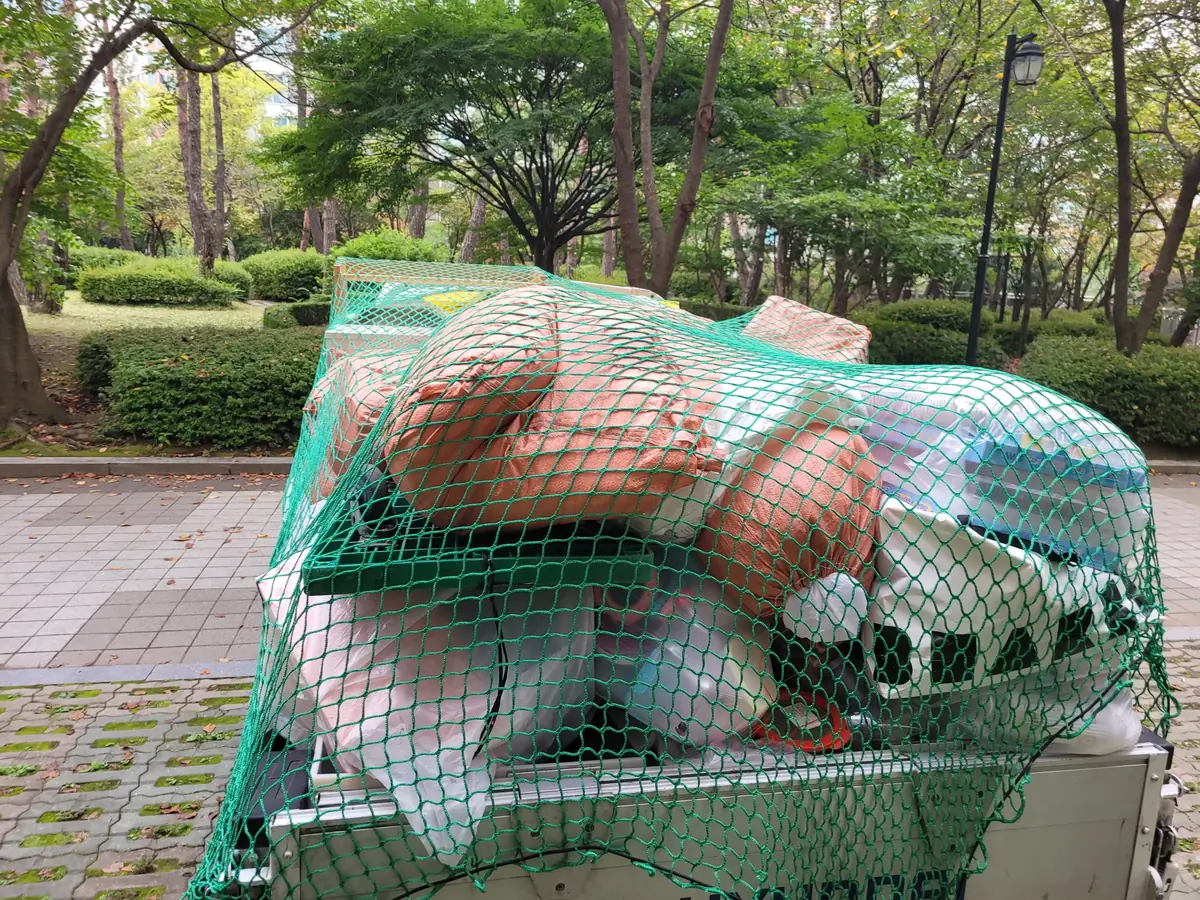 그물을 씌워 짐을 실은 수거 트럭